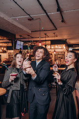 two young girls in black dresses and a curly haired guy have fun in a restaurant