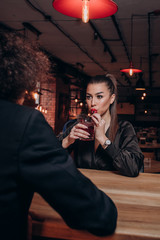 a young guy with curly hair and a beautiful girl in a dark dress with a glass of wine together in a restaurant