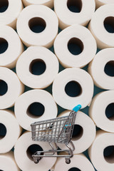 Supermarket shopping trolly on a background of toilet paper rolls