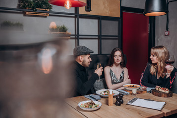 two beautiful young girls and a guy are sitting at a table in a restaurant