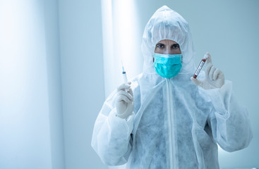 medico con tuta protettiva e mascherina tiene in mano una provetta per il test del sangue del...