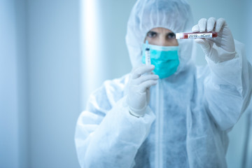 medico con tuta protettiva e mascherina tiene in mano una provetta per il test del sangue del...