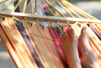 barefoot feet of the little girl while resting on the hammock in