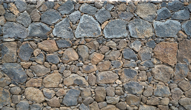 Beschaffenheit einer grauen und schwarzen Lava-Natursteinmauer als abstrakter Hintergrund