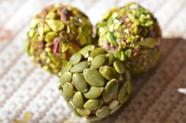 Close up of date covered with healthy pumpkin seeds, pistachio covered date pastries on the back