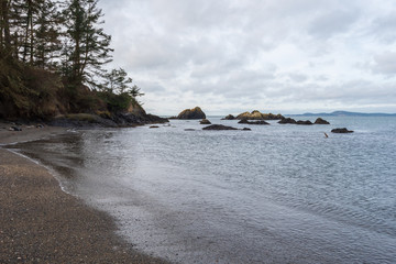 Obraz premium Landscape of beach, water, rocks and trees at Rosario Beach on Fidalgo Island in Washington