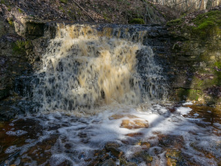 spring landscape with a small waterfall on a small wild river