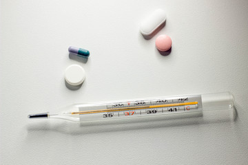 Angry smile of pills and thermometer on white background, the concept of a flu epidemic, medicine and healthcare. 