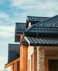 new roof, dark metal tile on a background of blue sky, structure, construction brick house