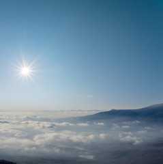 mountain ridge silhouette in a dense clouds under a sparkle sun, outdoor natural background