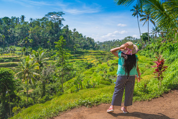 Female tourist enjoying the stepwise green rice field nature in a sunny day in Ubud, Bali