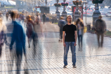 The young man stands in the middle of crowded street