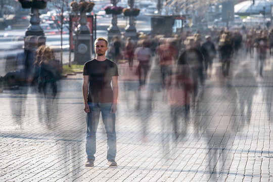 The young man stands in the middle of crowded street - Powered by Adobe