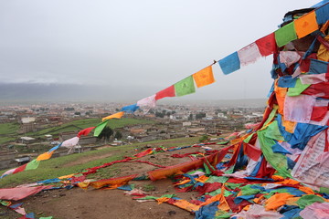 Tibetan town in China, Sichuan province. Flags on the mountain and view of the town in rainy season