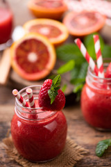Strawberry smoothie in glass jar, over old wood table.