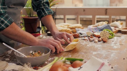 Man cooking empanadas argetinian pie, traditional bakery from argentina, chef filling dough in home with meat and vegetables, homemade spanish empanadas - Powered by Adobe