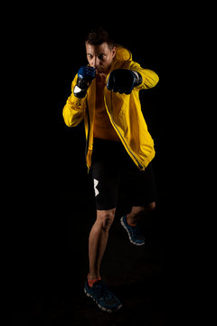 hombre musculoso con guantes de boxeo y anorak amarillo en fondo negro