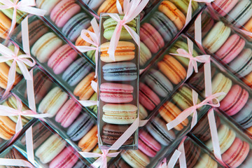 Macaroni cookies of different colors in a package with a bow, a lot of boxes with cookies in the form of texture.