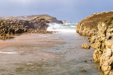 Beach between rocks on stormy day with lots of wind and waves, V