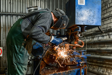 A welder is welding a steel billet for a pile.