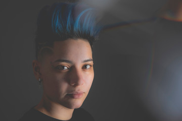 Portrait of lesbian punk woman with blue mohawk hairdo. Punk feminist female with sad expression....