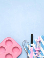 Cake pan, spatula, whisk, towel on a blue concrete background. A copy of the space.