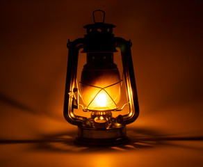 old kerosene lamp glows on dark white background with soft shadows