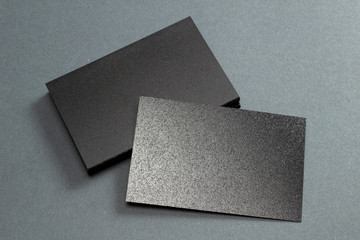 Black blank glossy textured stack of business cards on dark paper background, us size 3.5 x 2 inches, as template for design presentation.