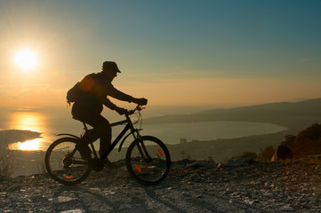 Fototapeta na wymiar Silhouette of cyclist riding on a bike in mountain at sunset