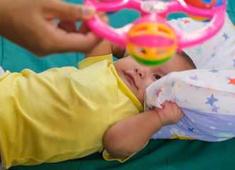 baby boy playing plastic toy for learning education while laying on bed.