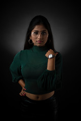 Fashion portrait of young and attractive Indian Bengali brunette girl with green cropped top and skirt in front of black studio background. Indian fashion portrait and lifestyle.