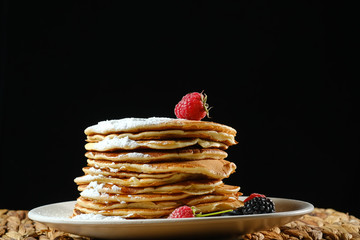Stack of pancakes with sugar powder.  On a dark background.  Copy space for your text.