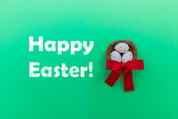 Minimalistic greeting card with chalk inscription Happy Easter and nest with three quail eggs