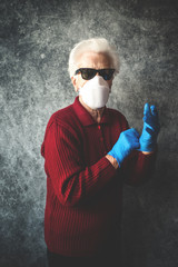 Old grandmother protect herself from coronavirus infection with medical gloves and respirator mask