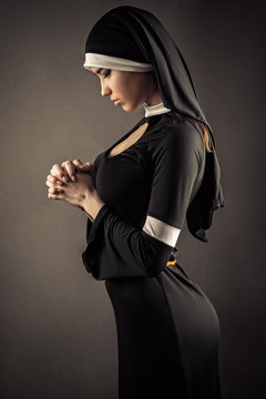 young nun in a black robe prays