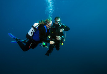 Happy couple scuba divers hovering together on a safety stop.