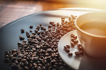 Coffee and coffee beans on black table.  Coffee beams closeup. Coffee theme. White cup on black table.