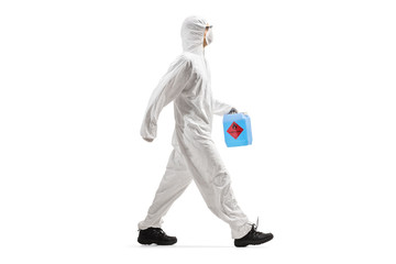 Man in a protective suit and mask holding a disinfectant containner and walking