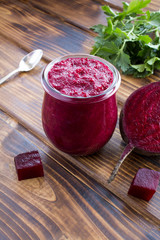 Smoothies or puree with beet in the small glass jar on the brown wooden  background. Location vertical.