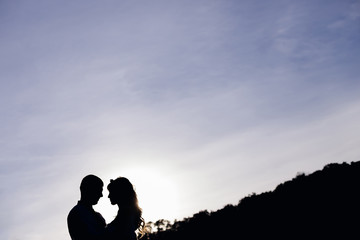 silhouettes of guy and girl on the background of the sky and tre