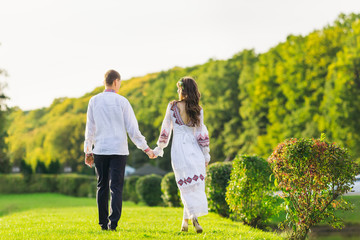 Fototapeta premium guy and girl in embroidered clothes holding hands and walking in