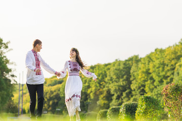 Naklejka na ściany i meble guy and girl in embroidered clothes holding hands and running in