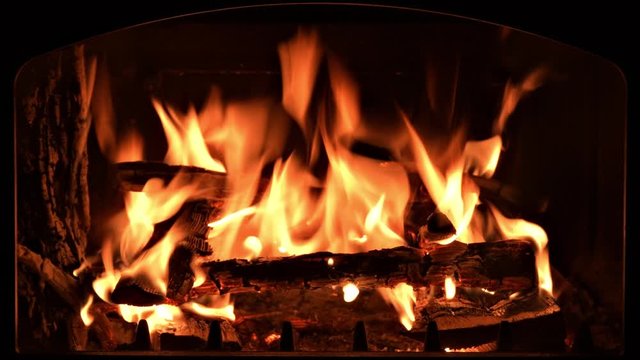 The fire burns in the fireplace. Background or screen saver for emitting a fireplace on electronic devices. You can see the frame of the door of the stove, inside the wood and coals.
