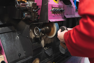 Shoemaker polishing the sole of a shoe with a disc on an electric machine
