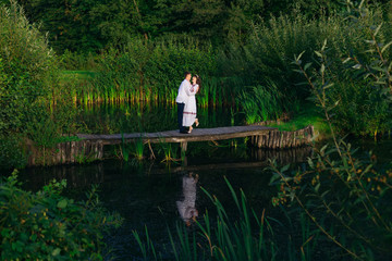 couple in embroidered clothes hugging on a wooden pier of a lake