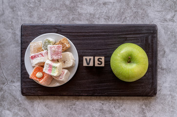 sweets versus apple top view on dark background