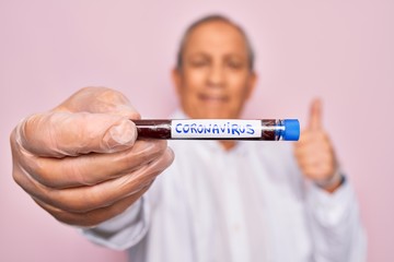 Senior handsome hoary man holding coronavirus tube test over isolated pink background happy with big smile doing ok sign, thumb up with fingers, excellent sign