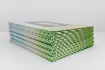 a large stack of blue-green books lies on a white surface. finished products of printed photobooks...
