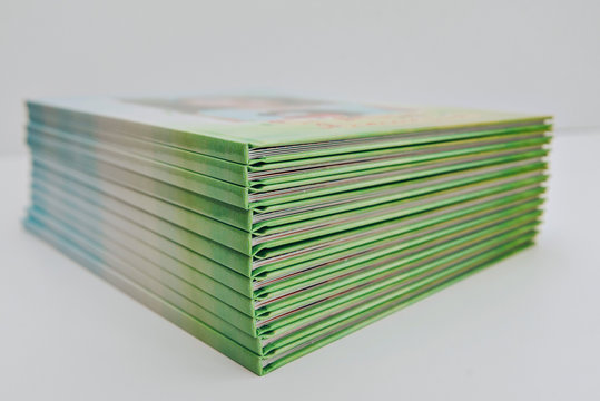 a large stack of blue-green books lies on a white surface. finished products of printed photobooks on a light background