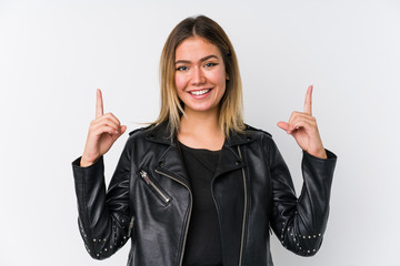Young caucasian woman wearing a black leather jacket indicates with both fore fingers up showing a...